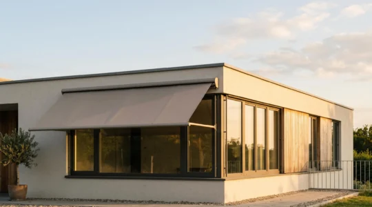 Façade de maison moderne équipée d'un store extérieur déployé protégeant une baie vitrée de la chaleur estivale